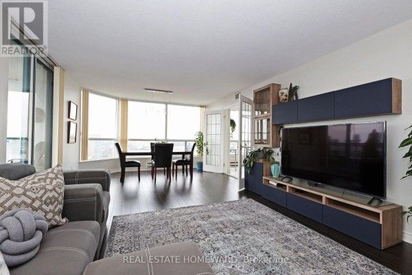 Living and dining area with dark wood floors, large windows, and a table for four. - 1913 - 4725 Sheppard Avenue E, Toronto