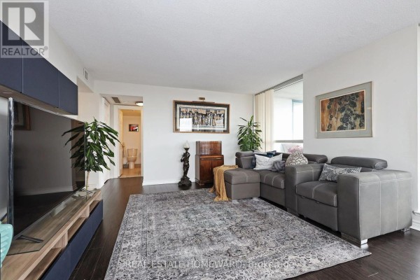 Living room showing a grey sectional sofa, entertainment unit, and a doorway to a bathroom. - 1913 - 4725 Sheppard Avenue E, Toronto