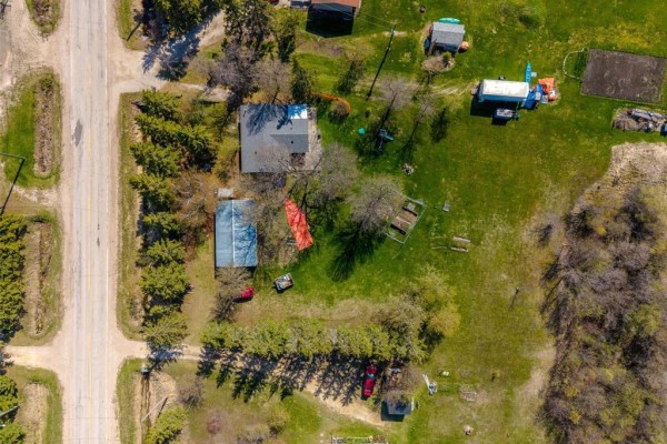 Exterior side view of a dark green house with a window and surrounding green trees. - 19155 Camp Morton Road, Gimli Rm
