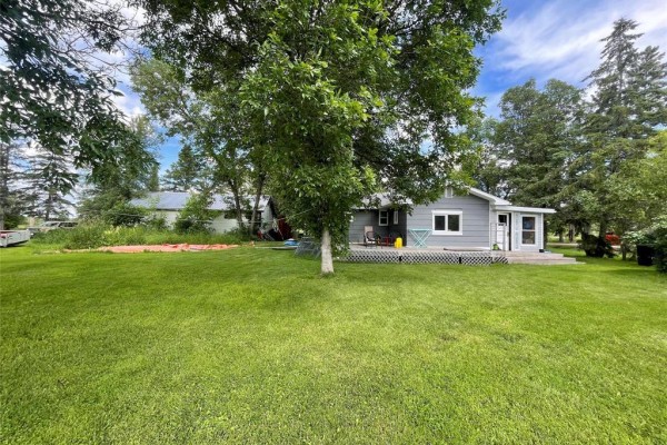 Aerial view of a grey house with a dark roof surrounded by green grass and trees. - 19155 Camp Morton Road, Gimli Rm