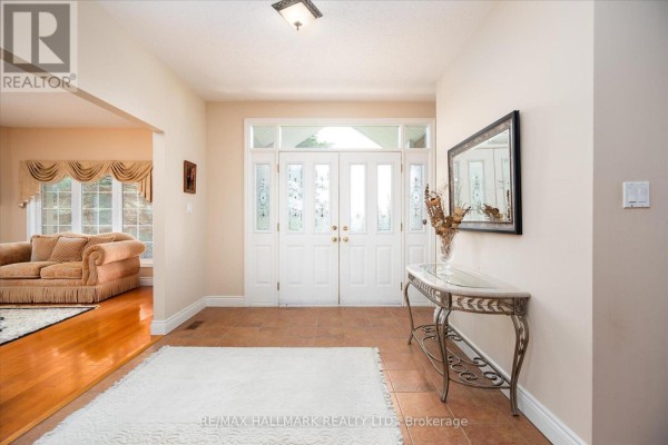 Foyer with tiled floor, white double doors, console table, and view into living room with hardwood floors. - 191555 13 Line, East Garafraxa