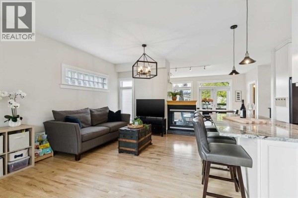 Living room with piano, armchairs, and view of trees through bay windows. - 1917 27 Avenue Sw, Calgary