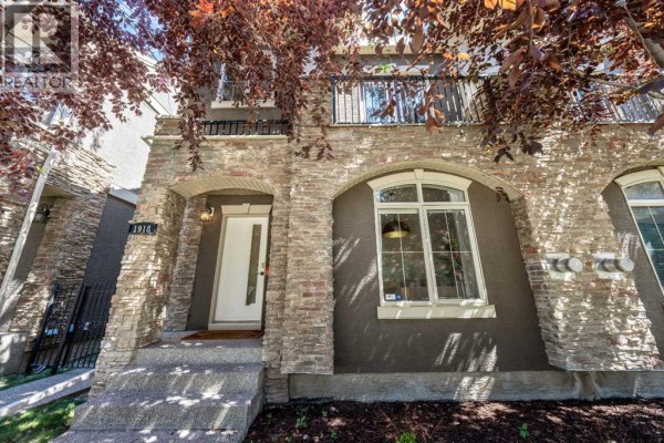 Close-up of the front entrance with a white door, stone accents and arched window. - 1918 36 Street Sw, Calgary