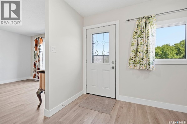 Interior hallway with a white door, light grey walls, and wood-look flooring. - 1919 14th Street W, Prince Albert