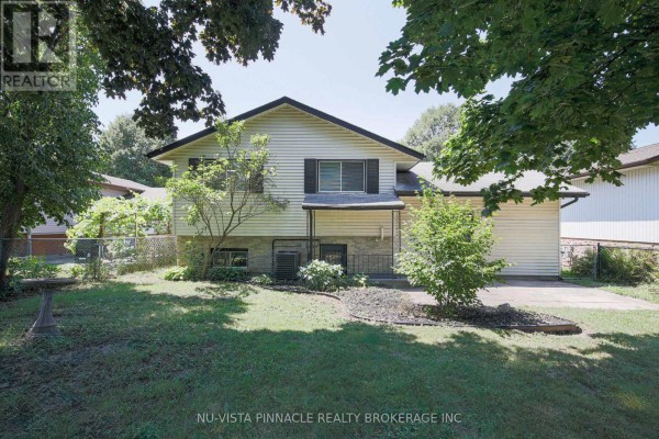 Rear exterior of a beige house with a dark roof, visible backyard, and attached garage. - 192 Concord Road, London North