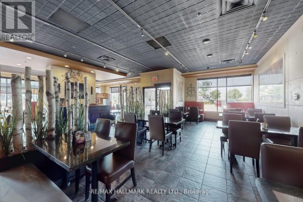 Interior dining area with dark furniture, large windows, and decorative plants - 192 Mcewan Drive E, Caledon