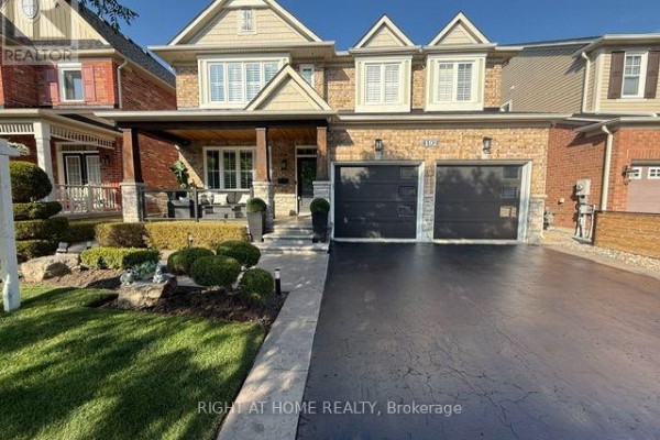 Front exterior of a large brick house during the day, with a paved driveway and manicured landscaping. - 192 Robirwin Street, Whitchurch Stouffville