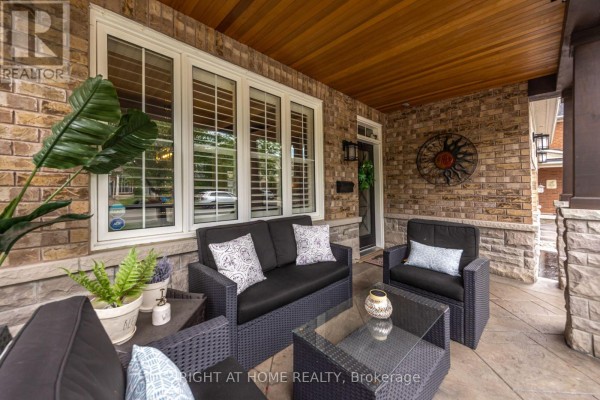 Covered front porch with wicker seating furniture and large windows with white shutters. - 192 Robirwin Street, Whitchurch Stouffville