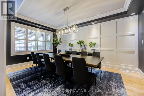 Formal dining room with a large wooden table, black chairs, and a rectangular chandelier. - 192 Robirwin Street, Whitchurch Stouffville
