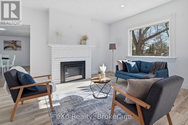 Living room with fireplace, blue sofa, armchairs, and coffee table - 192 William Street W North Middlesex