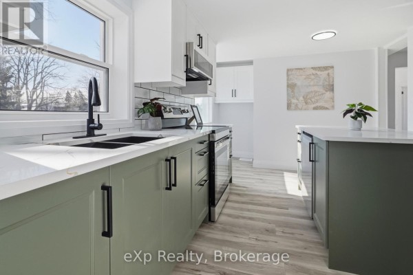 Modern kitchen with green cabinets, quartz counters, stainless steel appliances, and island - 192 William Street W North Middlesex