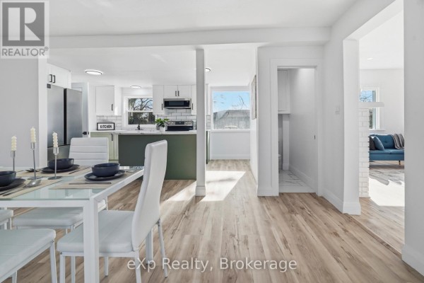 Modern kitchen with green island, dining area, and living room - 192 William Street W North Middlesex