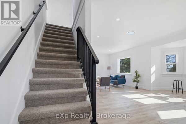 Carpeted stairs and open living area with blue sofa - 192 William Street W North Middlesex