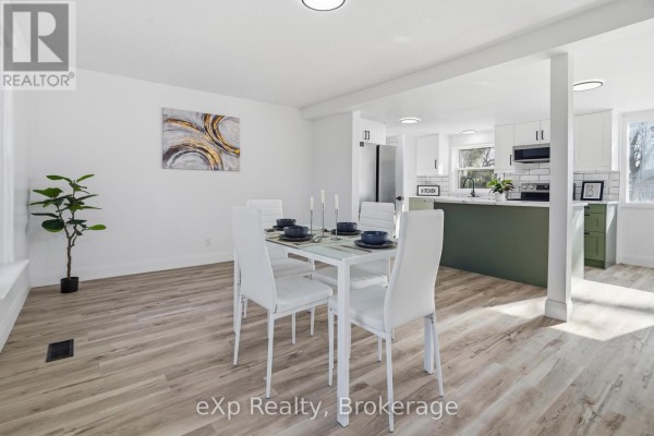 Dining room and open concept kitchen with white table, green island - 192 William Street W North Middlesex