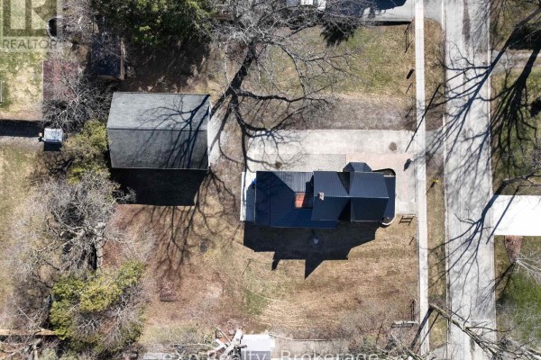 Aerial view of house with black metal roof, detached garage, and paved driveway - 192 William Street W North Middlesex