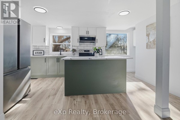 Modern kitchen with green island, stainless steel fridge, and white subway tile - 192 William Street W North Middlesex