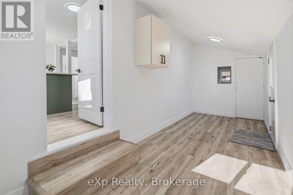Hallway with laminate flooring, cabinet, and door - 192 William Street W North Middlesex