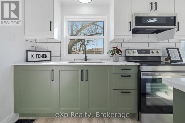 Modern kitchen with green cabinets, subway tile backsplash, and stainless steel appliances - 192 William Street W North Middlesex