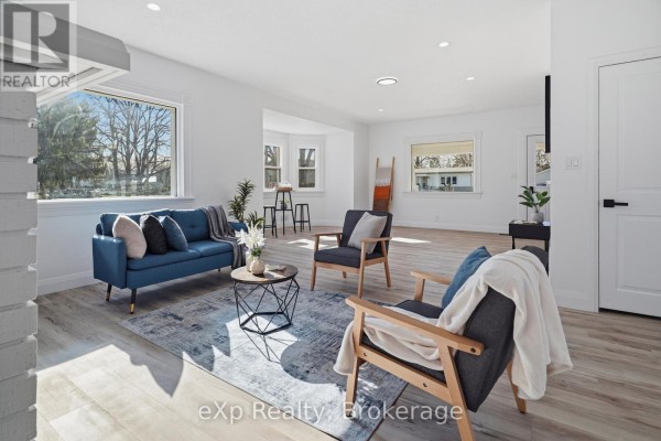 Living room with blue sofa, accent chairs, and large window - 192 William Street W North Middlesex