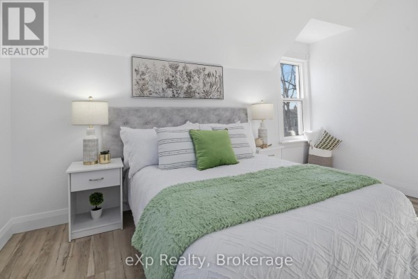 Bedroom with bed, nightstands, lamps, artwork, and window - 192 William Street W North Middlesex