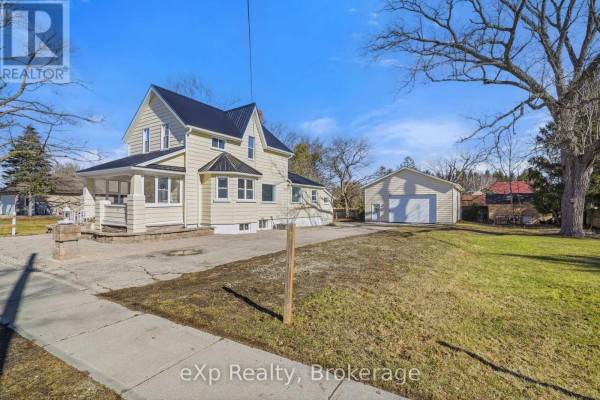 Yellow house with black metal roof and detached garage - 192 William Street W North Middlesex