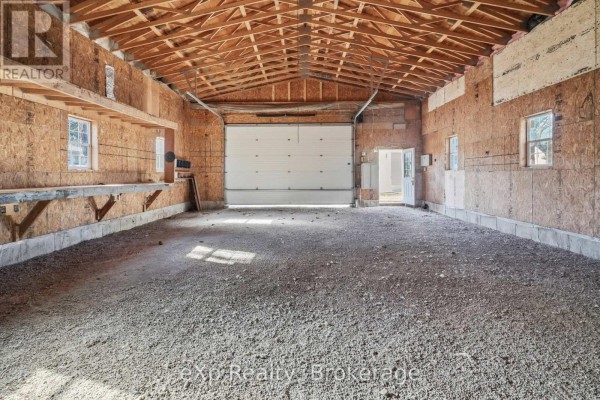 Spacious garage with overhead door, workbench, and unfinished walls - 192 William Street W North Middlesex