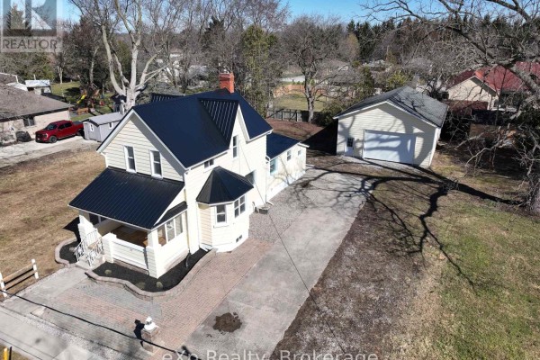Cream house with black metal roof, garage, and driveway - 192 William Street W North Middlesex