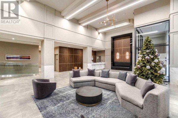 Spacious lobby with grey sectional sofa, modern chandelier, and festive Christmas tree. - 1920 - 4055 Parkside Village Drive, Mississauga