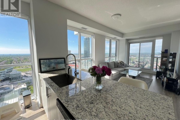 Kitchen counter with granite top, stainless steel sink, and view of living area. - 1920 - 4055 Parkside Village Drive, Mississauga