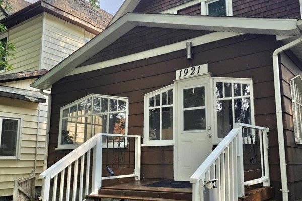 View of the brown house exterior from the side with trees in the foreground. - 1921 Garnet Street, Regina