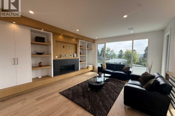 Hallway with a gold chandelier, white walls, and a wood railing. - 1924 10 Avenue Nw, Calgary