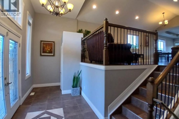 Interior foyer with tiled floor, staircase with dark wood banister, and chandelier. - 1926 Mark Avenue, Windsor