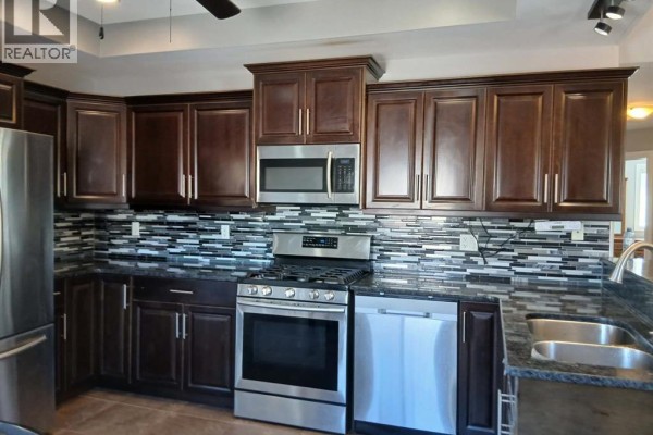 Dark wood kitchen cabinets, granite countertops, stainless steel appliances, and mosaic backsplash. - 1926 Mark Avenue, Windsor