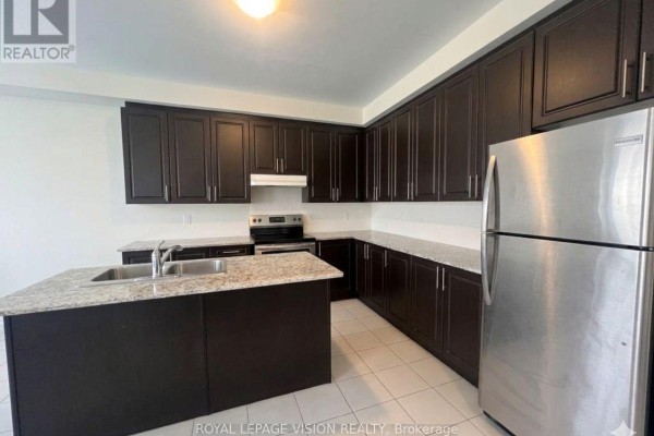 Kitchen with dark brown cabinets, granite countertops, stainless steel appliances, and an island. - 1929 Don White Court, Oshawa