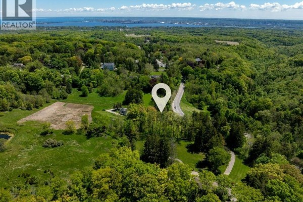 Aerial view of a large, wooded property with a winding road and distant view of Lake Ontario. - 193 Mill Street S, Waterdown