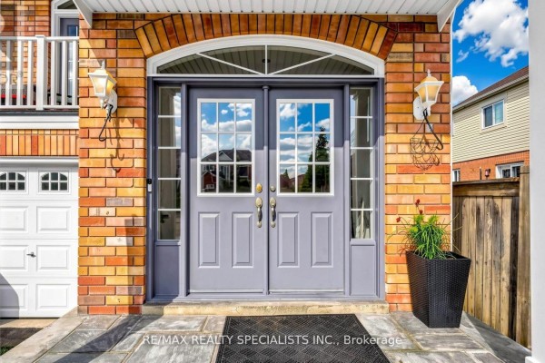 Detailed view of the double gray front doors with glass panels and sidelights on a brick house. - 193 Queen Mary Drive, Brampton