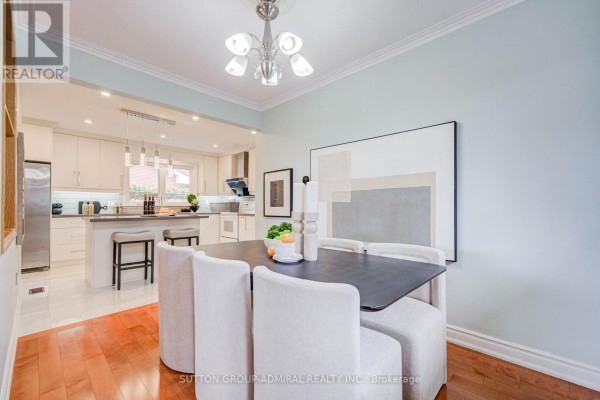 Dining area with a large abstract artwork, light blue walls, and view into the kitchen. - 193 The Westway, Toronto