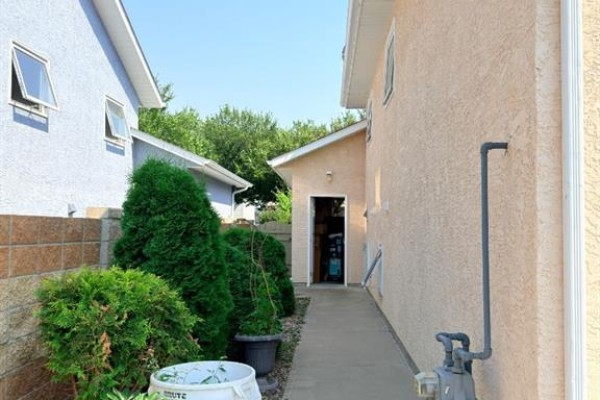 Side view of a house showing a concrete walkway between two residential buildings. - 193 Uplands Boulevard N, Lethbridge