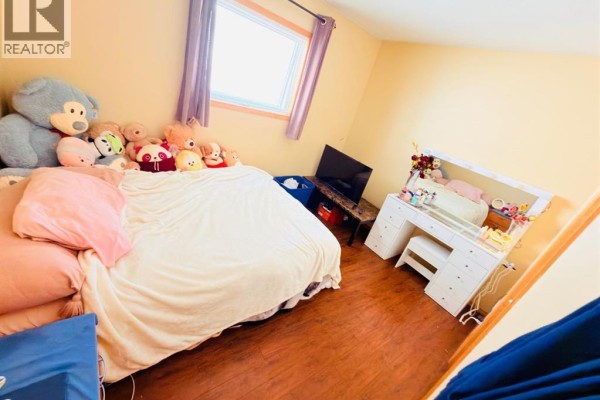 Bedroom with a large bed, stuffed animals, and a white vanity with a mirror. - 193 Uplands Boulevard N, Lethbridge