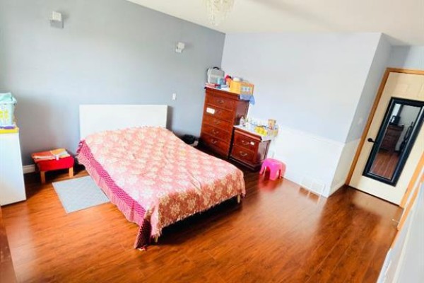 Bedroom with a single bed, dresser, and a tall mirror next to the door. - 193 Uplands Boulevard N, Lethbridge