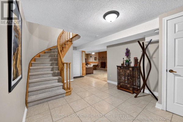 Tiled entryway with a carpeted curved staircase, a coat rack, and doors leading to other rooms. - 193 Wigwoss Drive, Vaughan