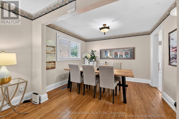 Dining room with a wooden table, upholstered chairs, hardwood floors, and a window overlooking greenery. - 193 Wigwoss Drive, Vaughan