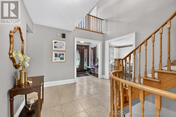 Foyer with light gray walls, tiled floors, a wooden console table, and a view of the front entrance. - 193 Wigwoss Drive, Vaughan