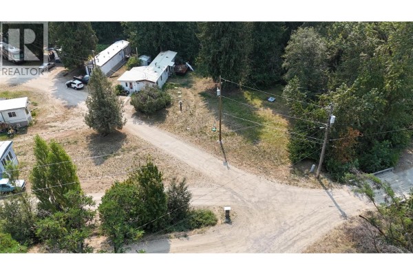 Aerial perspective of gravel roads winding through a manufactured home community with evergreen trees. - 1930 Setterland Road, Christina Lake