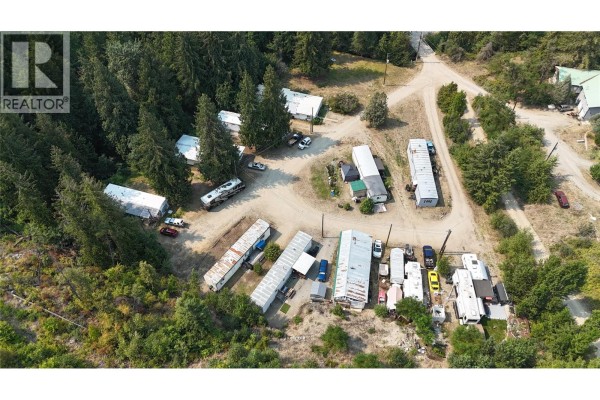 Wide aerial shot showcasing numerous mobile homes, RVs, and vehicles within a forested area. - 1930 Setterland Road, Christina Lake