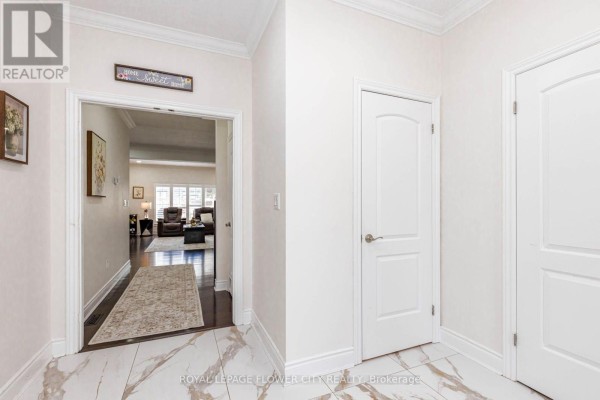 Interior hallway with tiled floor, white doors, and a view into a living room. - 1937 Jubilee Crescent, London North