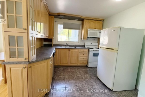 Kitchen with light wood cabinets, tiled floor, white appliances, and window. - 1939 St. Joseph Boulevard, Ottawa