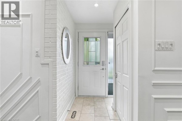 Interior hallway with white painted brick walls, a mirrored accent, and cream-colored tile flooring. - 194 Foxbar Road, Burlington