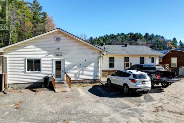 Compact kitchen with white cabinets, stainless steel appliances, a peninsula with a sink, and a wooden staircase. - 194 Hastings Street N, Bancroft