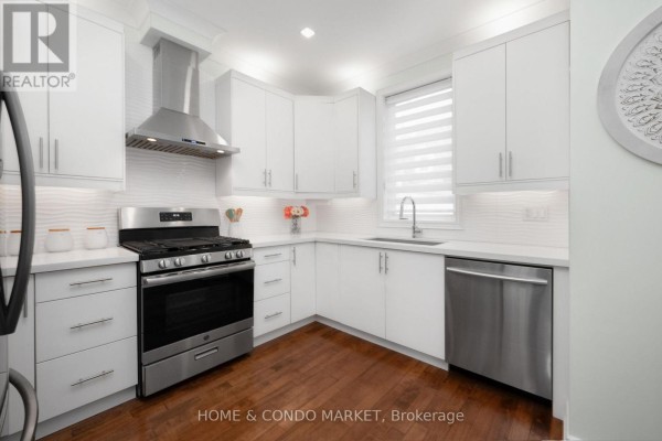 Corner kitchen with white cabinets, stainless steel appliances, and wood floors. - 194 Lakeshore Road W, Mississauga
